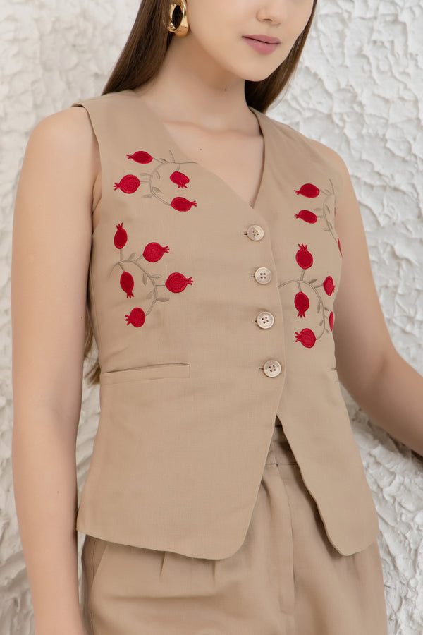 Beige sleeveless top with red floral embroidery on a textured white background