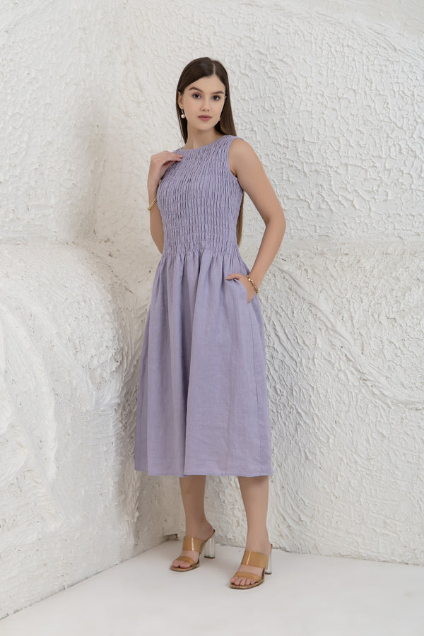 Woman wearing a light purple dress against a textured white wall.