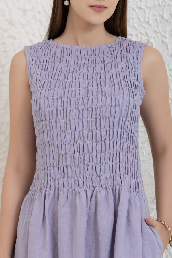 Woman wearing a light purple dress against a white textured wall