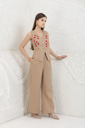 Woman wearing a beige outfit with red heart patterns against a white textured wall.