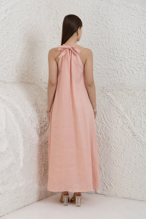 Woman wearing a long pink dress with a white textured wall background