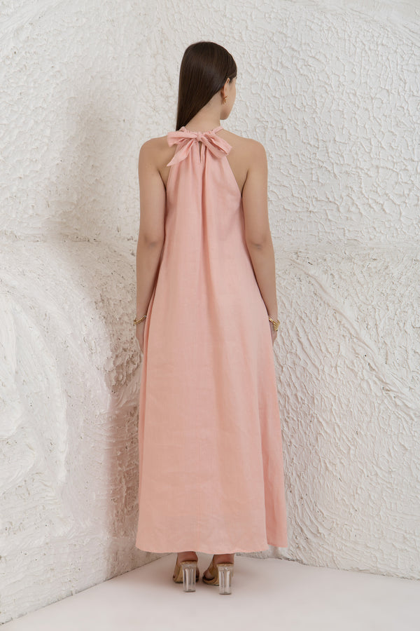 Woman wearing a long pink dress with a white textured wall background