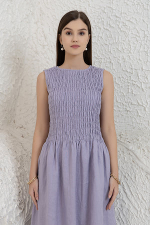 Woman wearing a light purple dress against a textured white wall