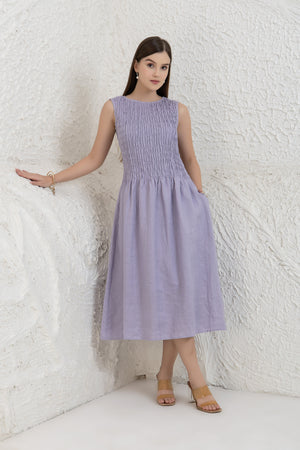 Woman wearing a light purple dress against a white textured wall.